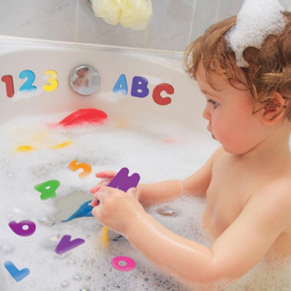 Baby playing with colorful foam bath letters and numbers stuck to bathtub wall during bath time