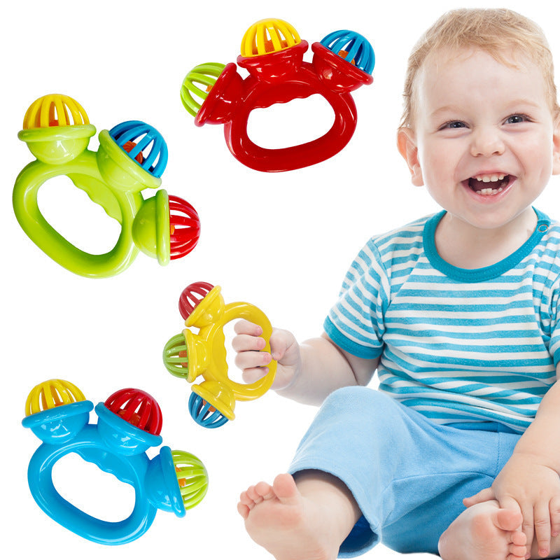 Smiling baby holding colorful handbell rattle toy showing easy-to-grasp ring handle design