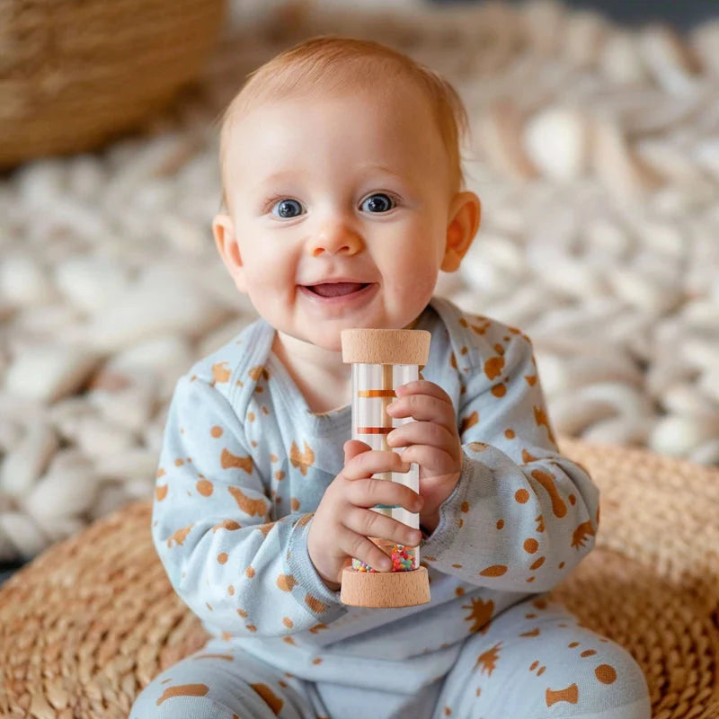 Smiling baby holding Montessori rain stick rattle toy showing easy-to-grasp size for small hands