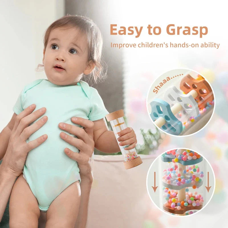 Smiling baby holding Montessori rain stick rattle toy showing easy-to-grasp size for small hands